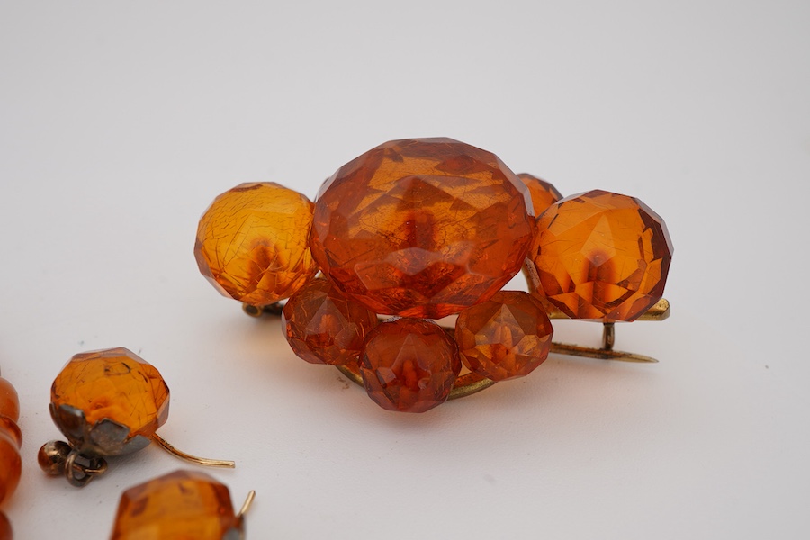 A single strand graduated oval amber bead necklace, 40cm, gross weight 9 grams, together with an amber cluster set brooch and pair of earrings.